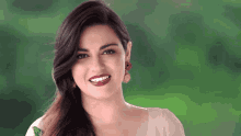 a woman wearing red lipstick and gold earrings smiles at the camera