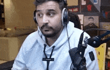 a man wearing headphones is sitting in front of a microphone in a room .