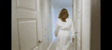 a woman in a white robe is walking through a hallway