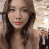 a woman with long brown hair is looking at the camera in a crowded room .