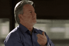 a man with gray hair and a blue shirt is talking