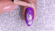 a person is applying purple nail polish to their nails .