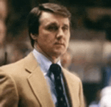 a man in a suit and tie is standing in a stadium .