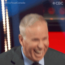a man in a suit and tie is laughing in front of a cbc logo