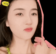 a close up of a woman 's face with a yellow g on her hair clip