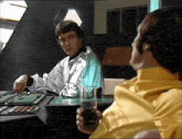 a man in a yellow shirt holds a glass of liquid