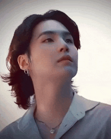 a close up of a man 's face with long hair and a necklace