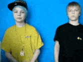 a boy wearing a yellow shirt with ny on it stands next to another boy wearing a black shirt