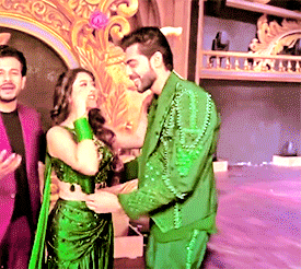a man in a green suit is shaking hands with a woman in a green dress .
