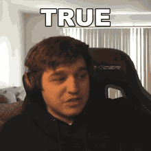 a man wearing headphones is sitting in a chair that says true