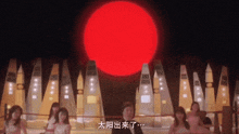 a man in a tuxedo is standing in front of a large red sun .