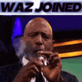 a man in a suit and tie is smoking a cigarette with the words waz joined above him