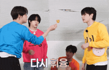a group of young men are standing in a room and one of them is wearing a yellow sweater that says ' i '