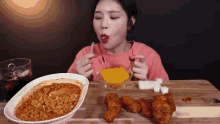 a woman is sitting at a table eating a bowl of rice and chicken