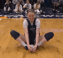 a huskies basketball player is sitting on the floor with her legs crossed