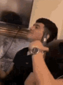a man is sitting on a couch talking on a cell phone while wearing a watch .