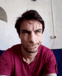 a man with a beard wearing a red shirt is making a funny face