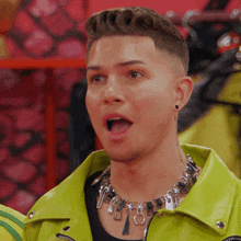 a man wearing a yellow jacket and a necklace with the letter o on it
