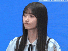 a girl with long black hair is wearing a blue shirt with a badge on the sleeve that says ' a ' on it