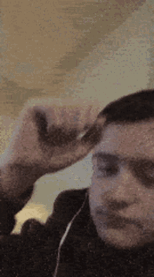 a man wearing headphones is scratching his head .