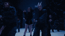 a group of people are dancing in a dark room and one of them is wearing a ring on her finger