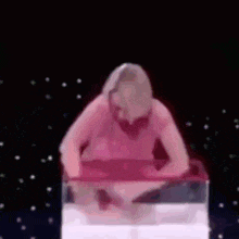 a woman in a pink dress is standing in a pink container .