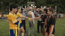 a group of soccer players are shaking hands on a field with referees .
