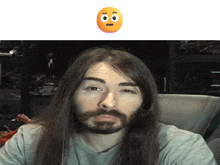 a man with long hair and a beard looks at the camera with an orange smiley face behind him