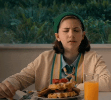 a girl wearing a green hat is eating waffles