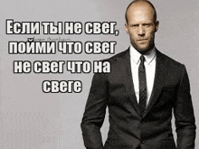 a man in a suit and tie is standing with his hands in his pockets and a quote in russian .