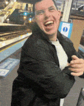 a man wearing a black jacket is laughing in front of a sign that says emergency