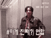 a man in a leather jacket is standing in front of a netflix logo