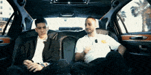 two men are sitting in the back of a limousine