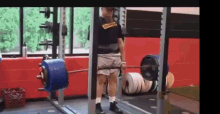 a man is lifting a barbell in a gym while standing in front of a mirror .