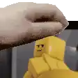 a close up of a person 's hand reaching for a yellow lego figure .