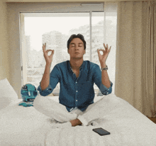 a man sits in a lotus position on a bed next to a helmet that says triumph on it