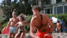 a man in red shorts with the word lifeguard on it is running on the beach