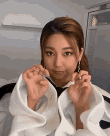 a woman is making a heart shape with her hands while wearing a white shirt