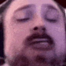 a man with a beard is wearing headphones and making a funny face .