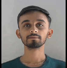 a young man with a beard is looking at the camera .
