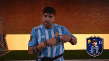 a man wearing a blue and white striped adidas jersey points to his chest
