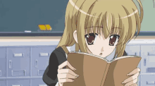 a girl with blonde hair is reading a book in front of a blackboard