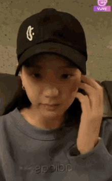 a woman wearing a black hat and a blue shirt with the word adidas on it