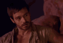 a man with a beard is standing in a dark room and looking at something .