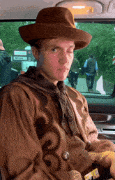 a man in a cowboy outfit is sitting in the back seat of a car