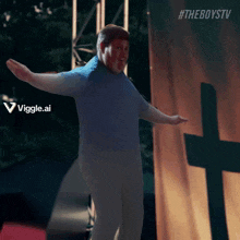 a man in a blue shirt is dancing in front of a cross with #theboystv written on it