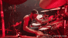 a man is playing drums in front of a crowd and the website gifrun.com is visible