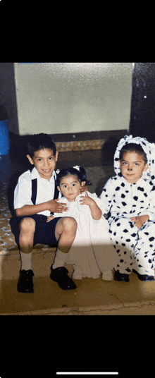 a boy and two girls are posing for a picture while one girl is dressed in a dalmatian costume