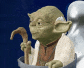 a statue of yoda is holding a cane in his hands