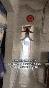 a girl is flying through the air in a hallway with a red clock on the wall